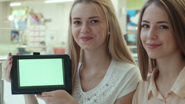 Two Girls Show The Tablet With The Green Screen 