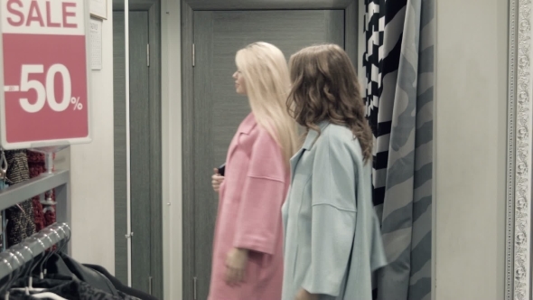 Two Girls Try On a Coat In a Locker Room