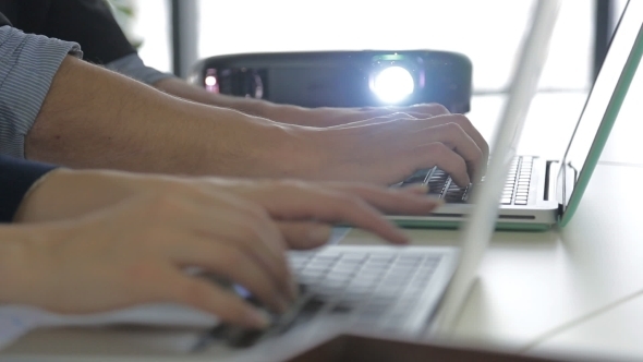 Laptop Computer And Two Colleagues Discussing Data