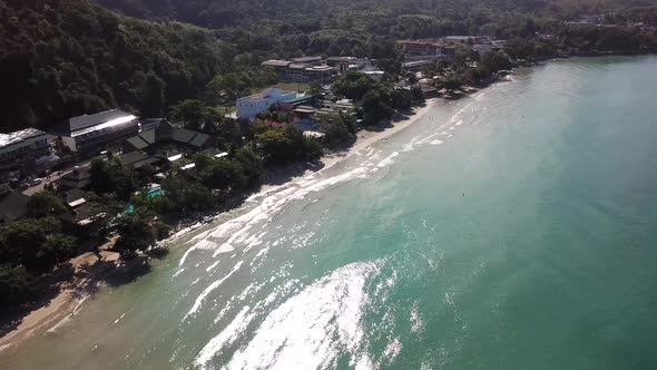 The green hills of the island are covered with palm trees, the sky is cloudy