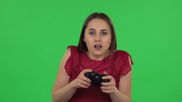 Portrait of Tender Girl Is Playing a Video Game Using a Wireless Controller and Rejoicing in Victory