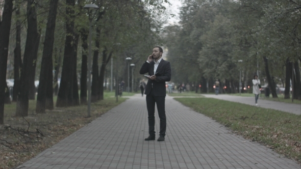 Young Business Man In Park Alley Talking By Phone