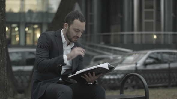 Man In Suit Reading Business Plan With Interest alt
