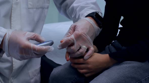 Young Asian male doctor measuring blood sugar level of boy with glucometer 4k