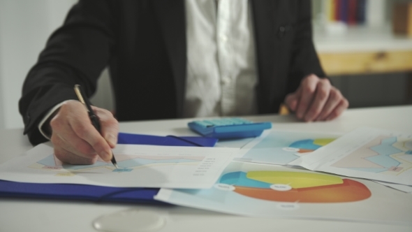 A Man Looks At The Charts And Using A Calculator alt