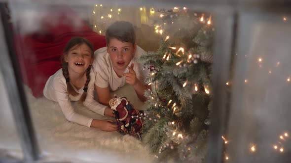 Festive Christmas Holidays scene - children play with sleigh filmed through window