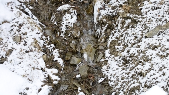 Small Mountain Brook Flowing On Stony Snow Covered
