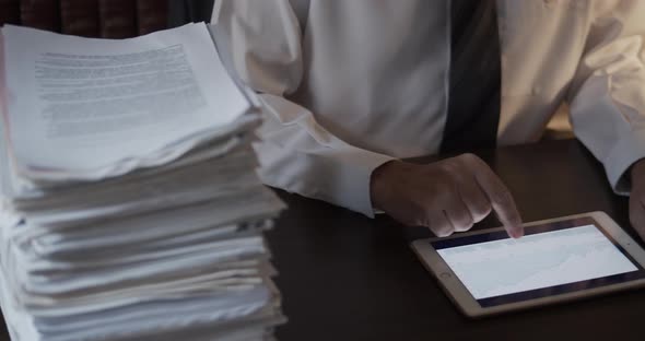 Man Reviewing Graphs in His Tablet at the Office Desk