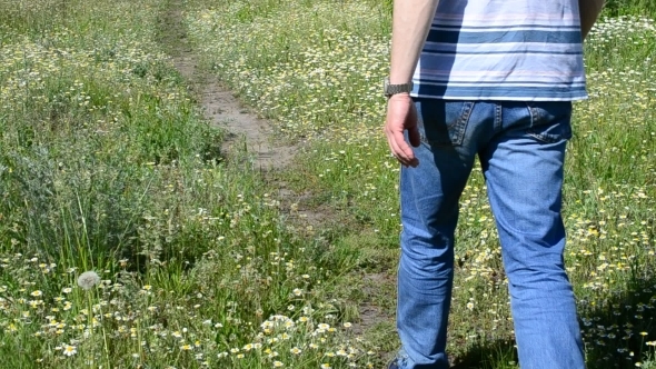 Feet Of Young Man In Blue Jeans Walking On Path In