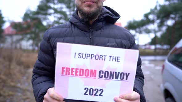 Closeup of a Young Man in a Black Jacket Holding a Poster with the Inscription I Support the Freedom