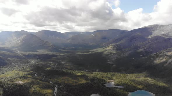 Top View of a Mountain Valley with Forests Around a Small Lakes and a Dirt Road