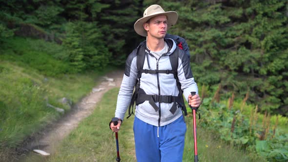 Portrait of Millennial Traveler Male Tourist with Trekking Sticks and Tourist Backpack Coming Out of