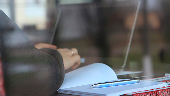 Man Working on Laptop and Writing In a Notebook