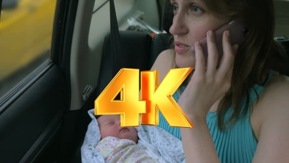 Woman With Baby In Hands Talking On Phone