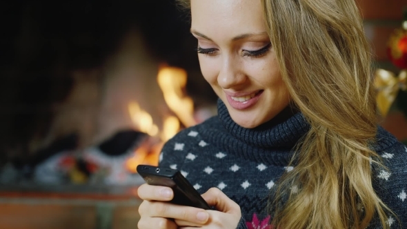 Girl Near The Fireplace With Your Smartphone