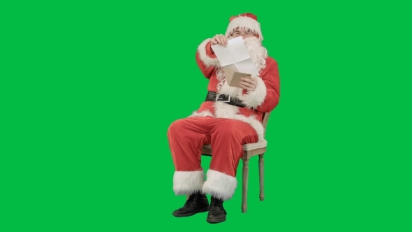 Santa Claus Sitting On Chair With Letters In Hands