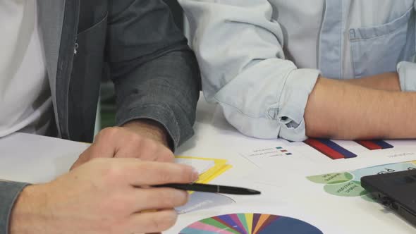 Cropped Shot of Two Business Colleagues Talking Examining Documents