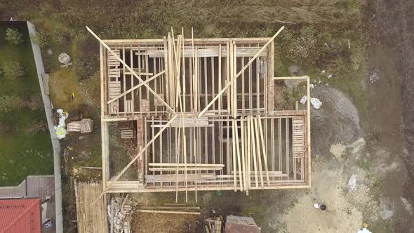Top down aerial view of a house under construction with wooden roof frame.