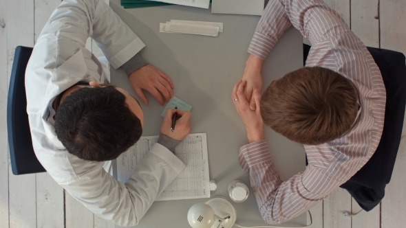 Top View Of Doctor Writing On a Medical Chart  alt