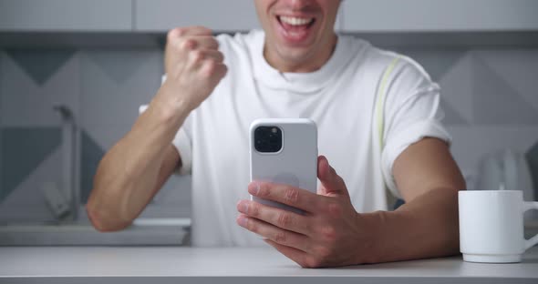 Closeup of a Happy Man Rejoicing at Winning on a Mobile Phone