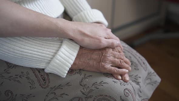 Worried man taking and gently stroking hand of his grandmother showing care and love