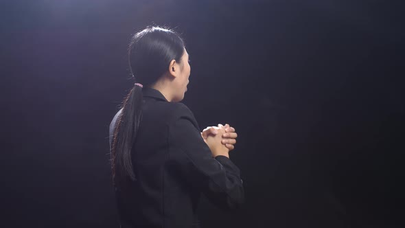 Back View Of Asian Speaker Woman In Business Suit Holding Her Hands Together While Speaking On Stage