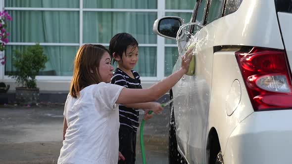 Asian Mother And Son Washing Car Together On Summer Day Slow Motion