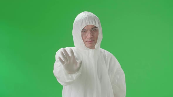 Asian Man Wearing Protective Uniform Ppe And Showing Hand Stop Sign In The Green Screen Studio