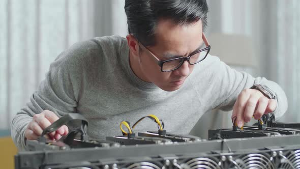 Close Up Of Asian Man Connects The Power Cords Of Mining Rig For Mining Cryptocurrency