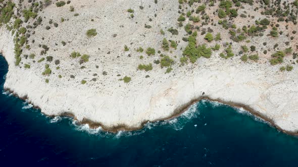 Drone Flying Over Rocky Coast Line with Deep Blue Sea Water