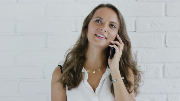 Cheerful Woman with Wavy Hair Speaking on Smartphone