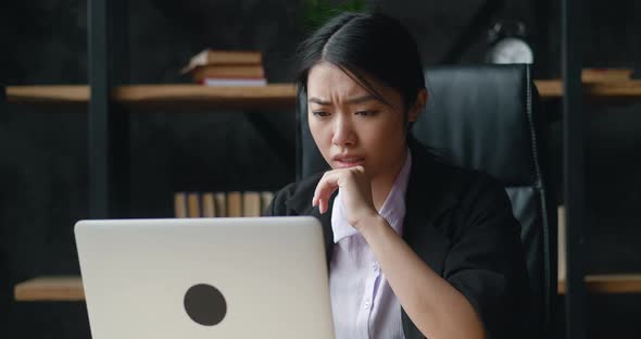 Shocked Asian Businesswoman Upset with Bad Deal Looking at Laptop Screen Reaction on Crisis