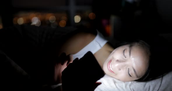 Woman using cellphone on bed