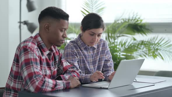 African Man and Indian Woman Reacting to Loss on Laptop