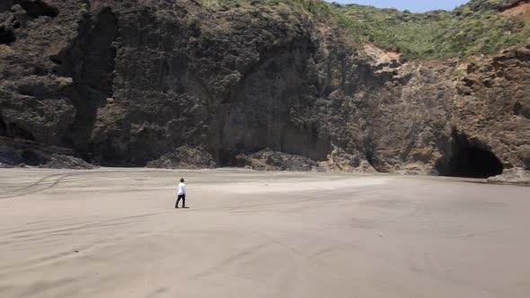 Man Walking On The Scenic Coast Of Bethells Beach In North Island, New Zealand - aerial drone shot