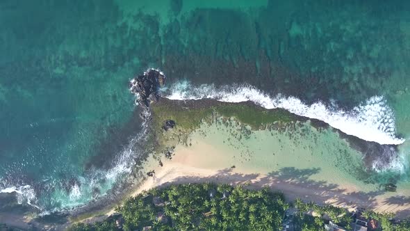 Foaming Ocean Waves Roll on Sandy Coastline with Green Grass