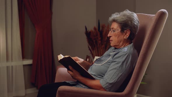 Elderly woman reading a book at home.