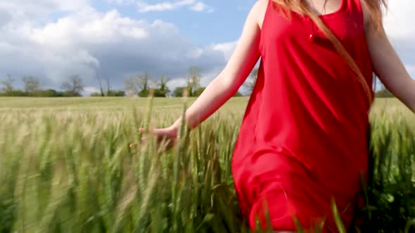 girl with red dress in a green wheat field