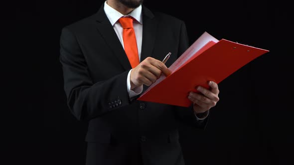 Man Fills Papers in Red Folder with Pen, Then Looks Through Them. Concept of Planning, Business