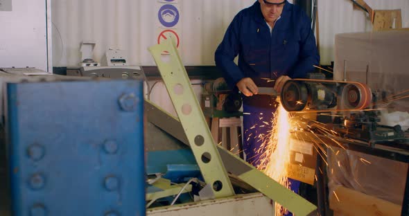 Worker shaping metal on machine 4k