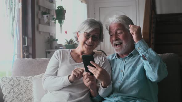 Overjoyed middle aged mature family couple looking at laptop screen, celebrating