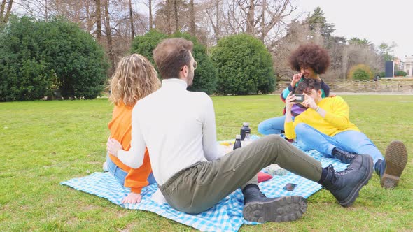 Four cheerful friends diverse multiethnic having fun doing pic nic in a park
