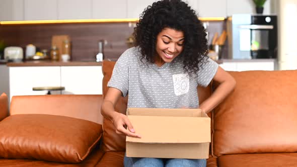 Overjoyed Young AfricanAmerican Female Unpacking Cardboard Parcel Box