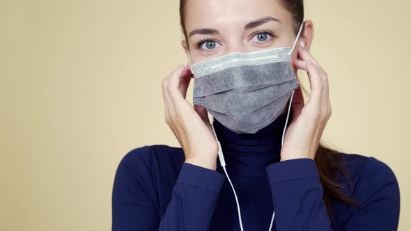 Young Woman Listening Music in Earphones and Dancing in Medical Protection Mask