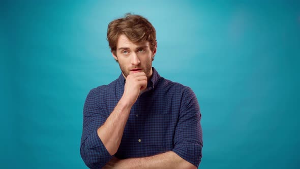 Thoughtful Young Man Has an Idea Pointing Up Blue Background