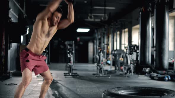 A Strong Sportsman is Hitting Huge Tire with Sledgehammer