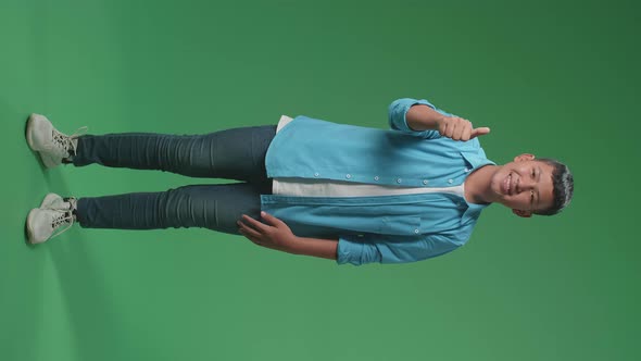 Full Body Of Happy Asian Boy Showing Thumbs Up Gesture While Standing In The Green Screen Studio