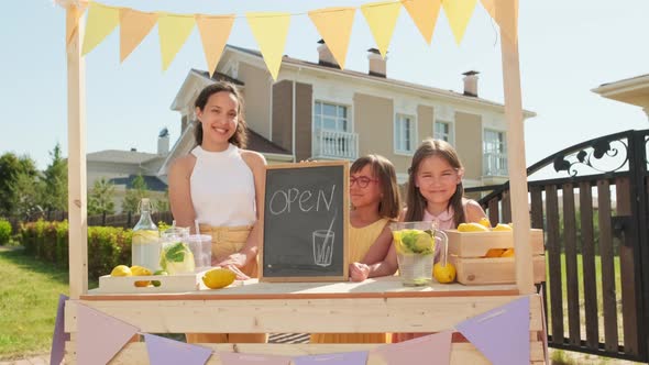 Mom And Daughters Selling Lemonade At Market