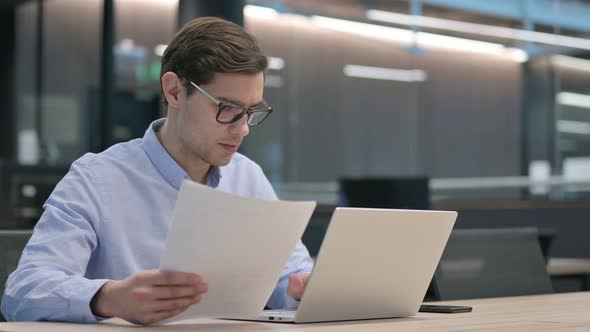 Young Man Having Loss on Documents While Using Laptop