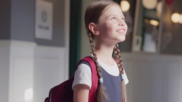 Portrait of Happy Schoolgirl Standing Near Window in School Corridor Enjoying Sunshine